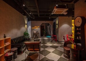 A cozy lounge area with a checkered floor, leather furniture, a staircase, and a clock on the wall. - IForest hotel - Shanghai People's Square (Shanghai)