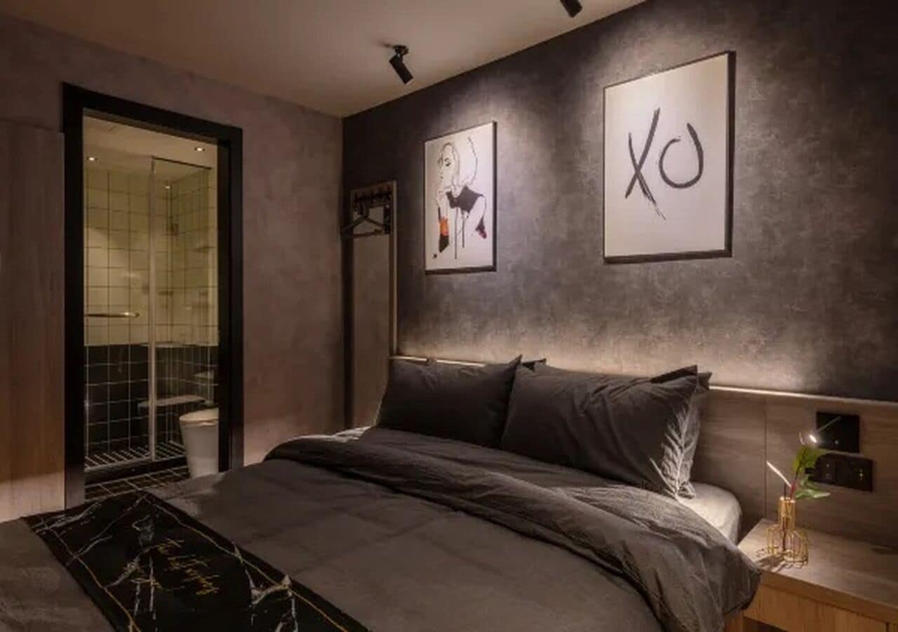 A modern bedroom with a large bed, a bedside table, and a wall-mounted artwork.