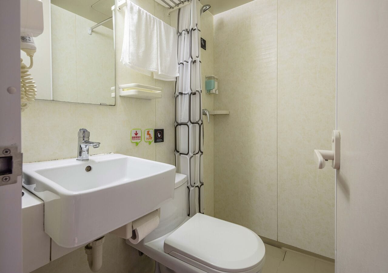 A bathroom with a white sink, toilet, and shower curtain.