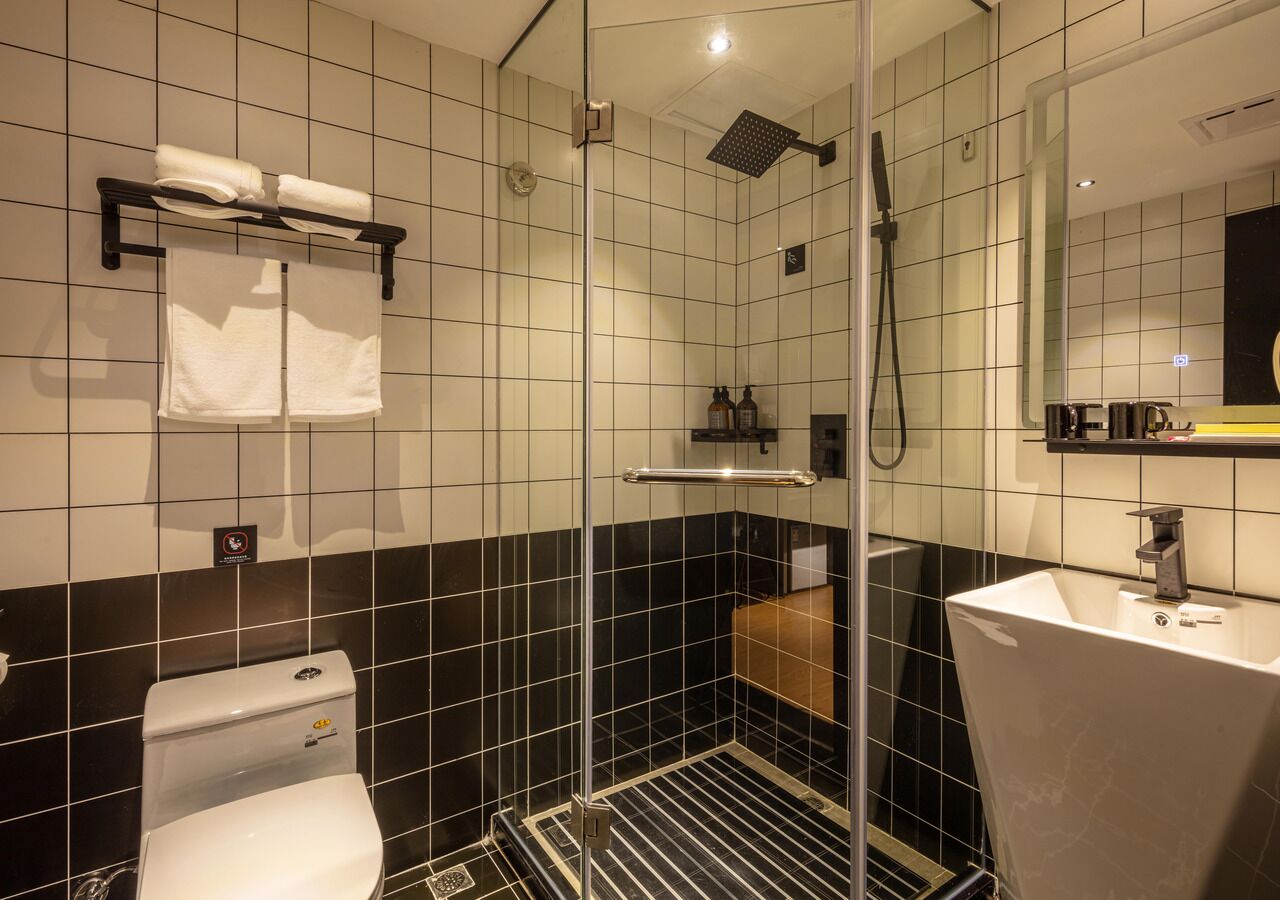 A modern bathroom with a glass-enclosed shower, a toilet, a sink, and a towel rack.