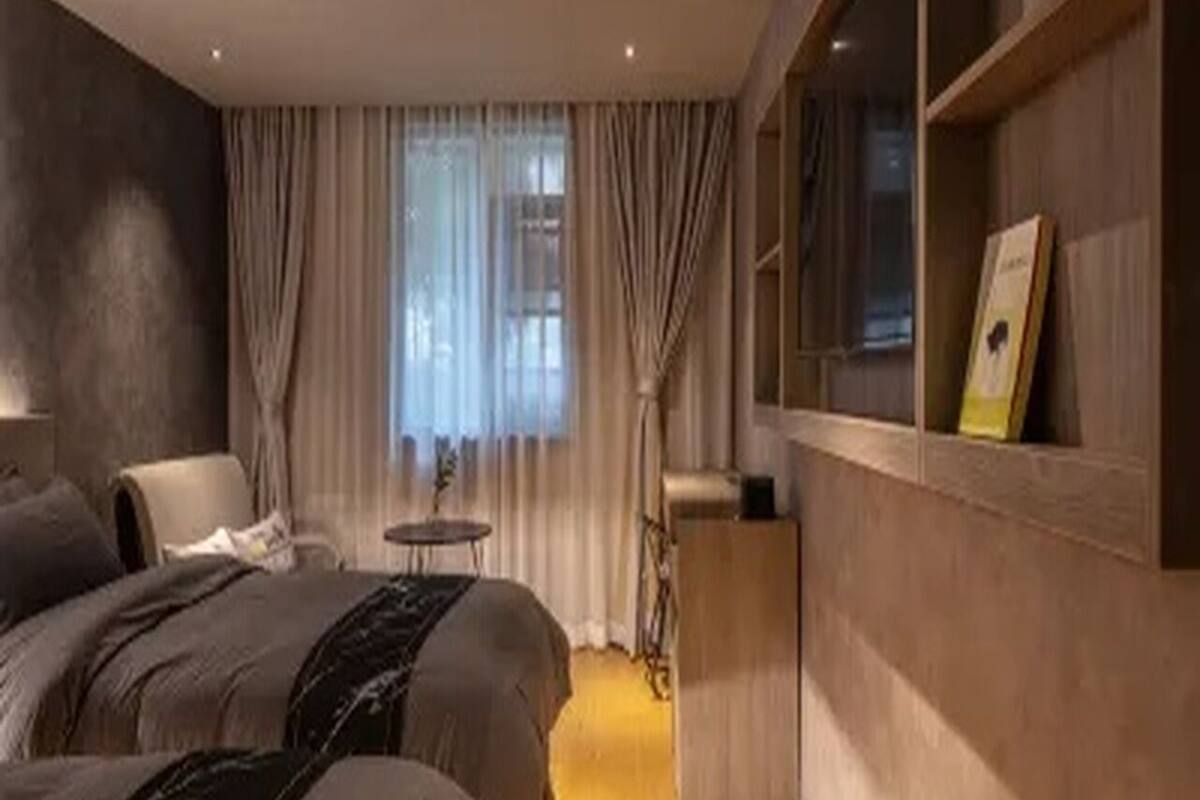 Una habitación de hotel moderna con una cama, un escritorio, una silla y un ventanal con cortinas.