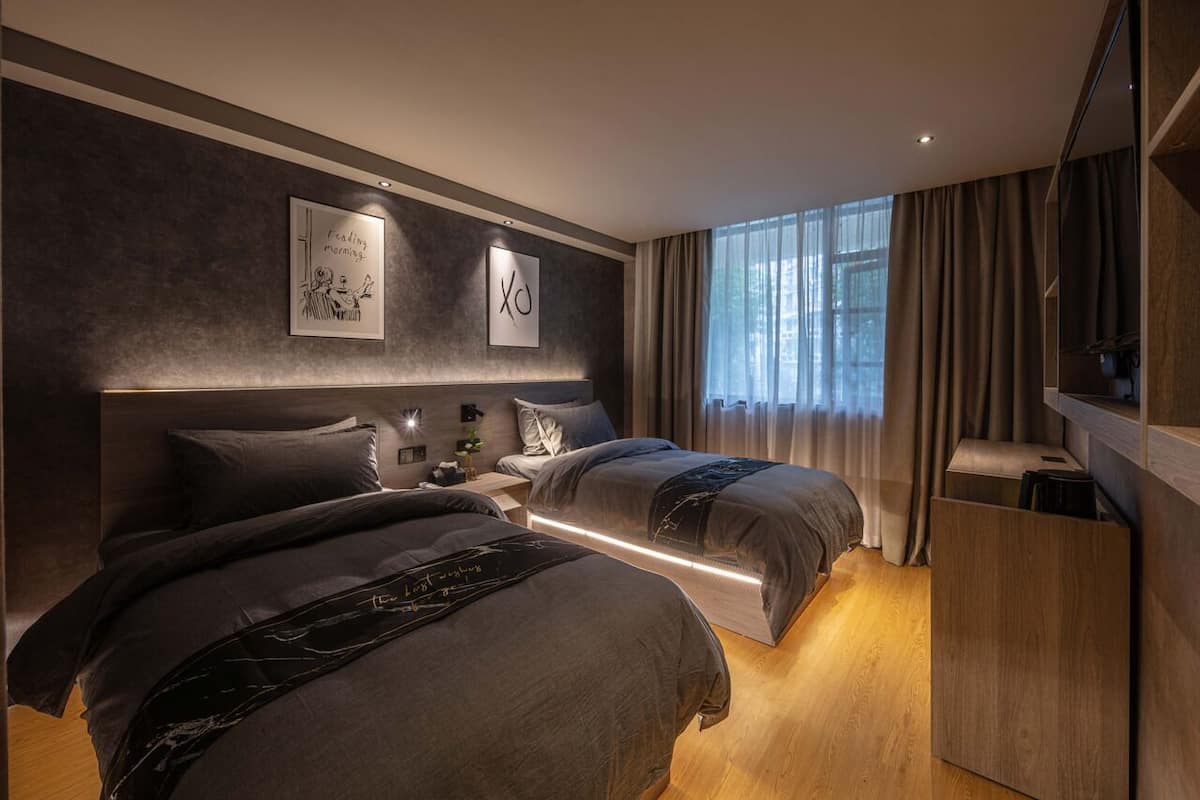 Un dormitorio moderno con dos camas, un ventanal con cortinas y un armario de madera.