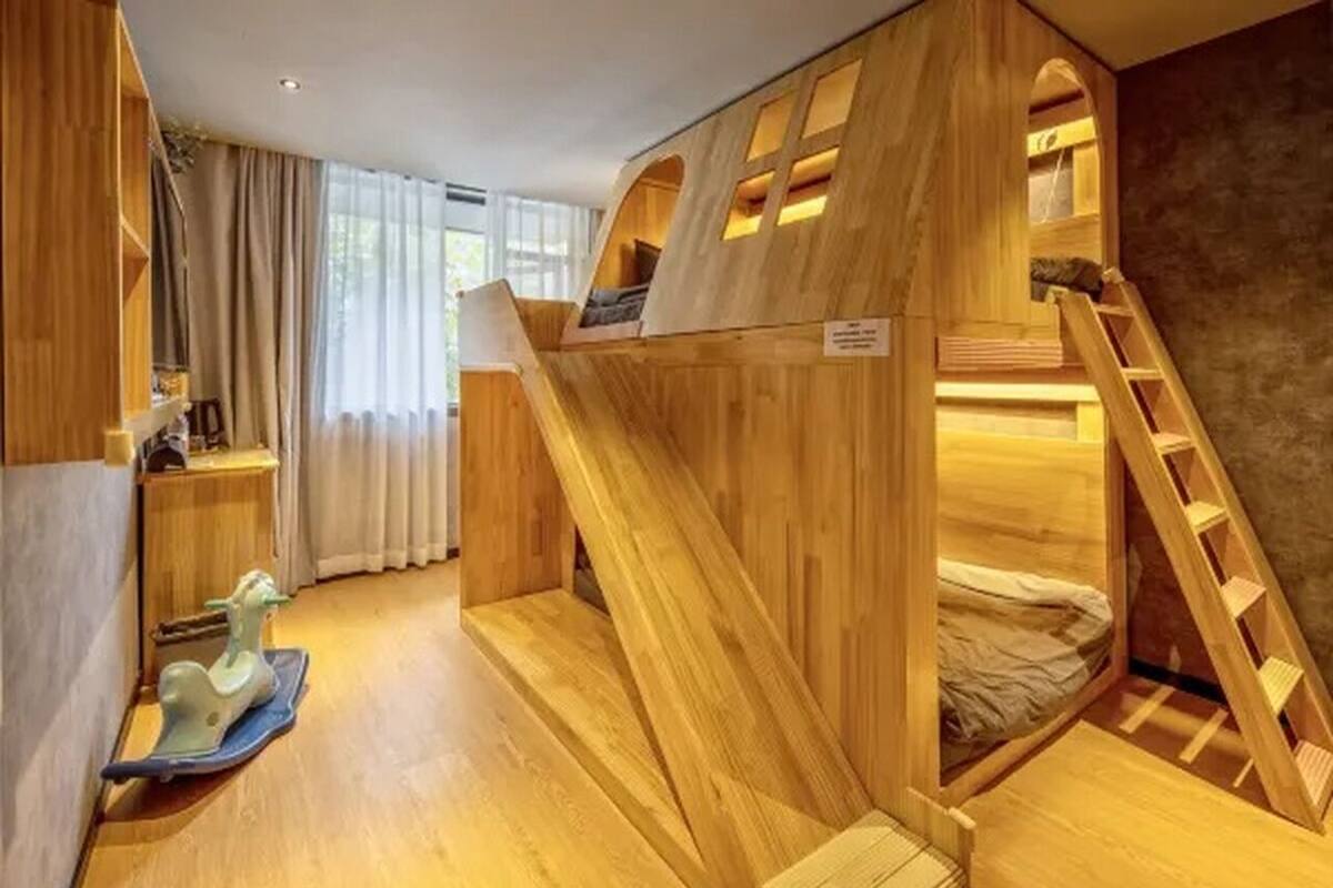 Una cama litera de madera con una escalera, un escritorio pequeño y un caballo de juguete.