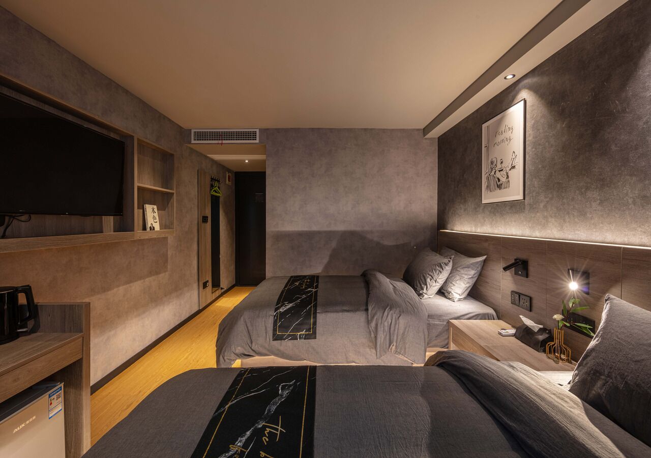 Et moderne hotelværelse med en stor seng, en mindre sofa, et fjernsyn og et kunstværk på væggen.