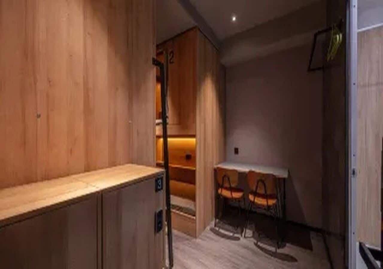 A room with a wooden cabinet, a table with chairs, and a small seating area with a bench.