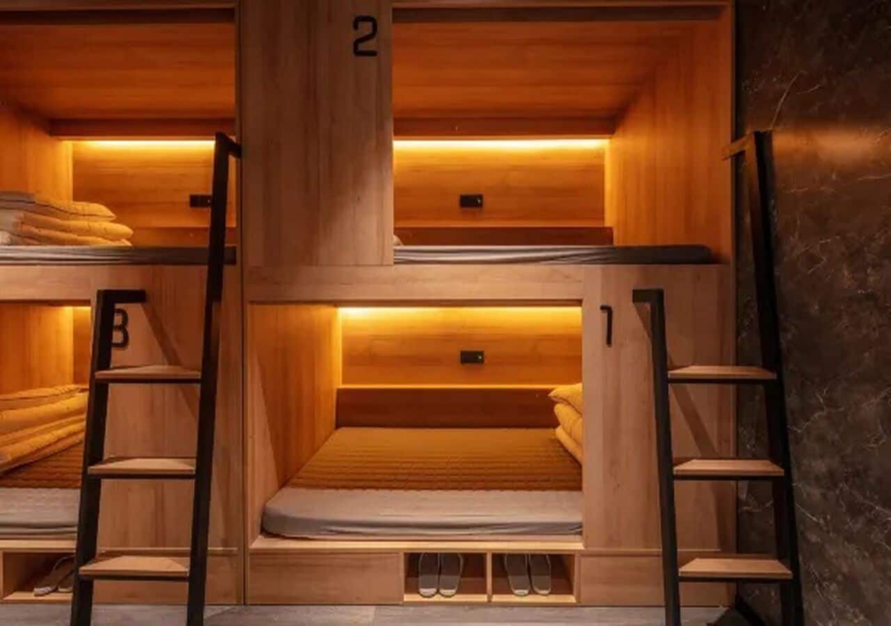 Une chambre avec un lit superposé en bois, dotée d’étagères intégrées et d’une échelle.