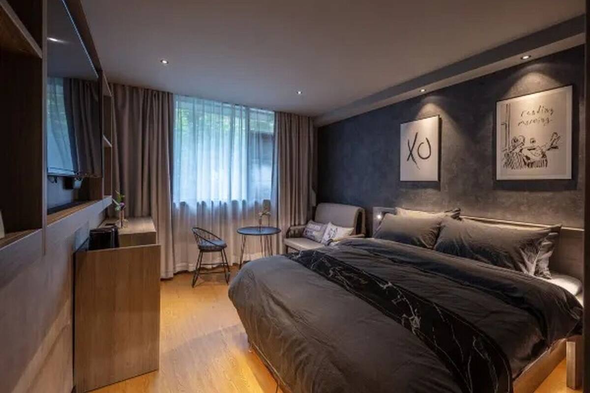 Una habitación de hotel moderna con una cama, un escritorio, una silla y una mesita.