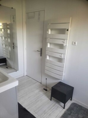 A bathroom with a white door, a mirror, a towel rack, a small stool, and a light switch on the wall. - 300m from the sea, 75 m² enclosed garden apartment for 4 people (La Seyne-sur-Mer)