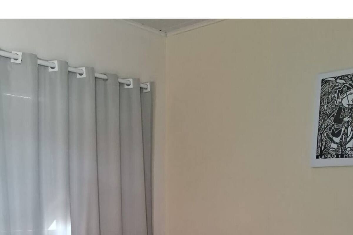 A hotel room with two beds, a curtain, a framed artwork, and a tiled floor.