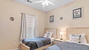 A bedroom with two beds, a ceiling fan, and a nightstand with a lamp. - Family Friendly Coastal Escape (North Myrtle Beach)
