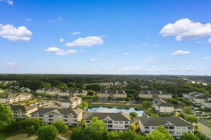 A residential area with multiple apartment buildings, a central pond, and a clear sky. - Family Friendly Coastal Escape (North Myrtle Beach)