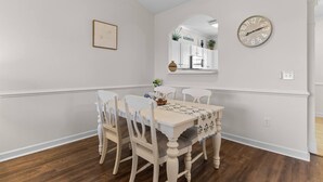 A dining area with a table and chairs, a clock, and a framed picture on the wall. - Family Friendly Coastal Escape (North Myrtle Beach)