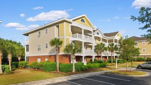 A multi-story hotel with a central courtyard, balconies, and a parking lot. - Family Friendly Coastal Escape (North Myrtle Beach)