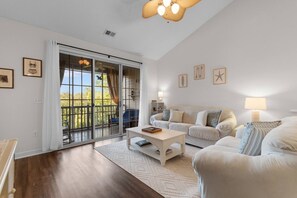 A living room with a sofa, a coffee table, and a view through a sliding glass door to an outdoor deck. - Family Friendly Coastal Escape (North Myrtle Beach)