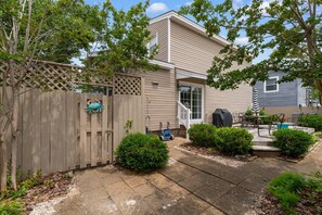 A residential house with a wooden fence, a covered patio with outdoor furniture, and a lawn. - North Myrtle Beach Cottage 2 Blocks From Beach (North Myrtle Beach)