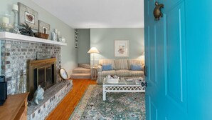 Una sala de estar acogedora con chimenea, una puerta azul, un sofá a rayas y una alfombra estampada.