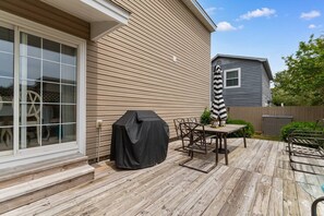 A wooden deck with a barbecue grill, outdoor table, and chairs. - North Myrtle Beach Cottage 2 Blocks From Beach (North Myrtle Beach)