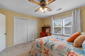 A bedroom with a bed, a ceiling fan, a window with blinds, and a door. - North Myrtle Beach Cottage 2 Blocks From Beach (North Myrtle Beach)