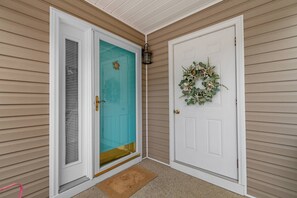 A house entrance with a teal door, a white door with a wreath, and a small porch area. - North Myrtle Beach Cottage 2 Blocks From Beach (North Myrtle Beach)