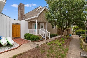 A residential property with a front porch, a wooden fence, and a pathway leading to the house. - North Myrtle Beach Cottage 2 Blocks From Beach (North Myrtle Beach)
