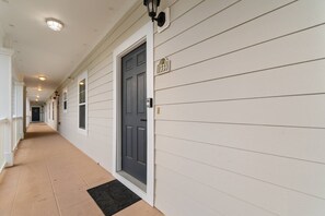 A corridor with a dark door, a mailbox, and a house number sign. - Top-Floor Barefoot retreat | Nature views + Pool (North Myrtle Beach)