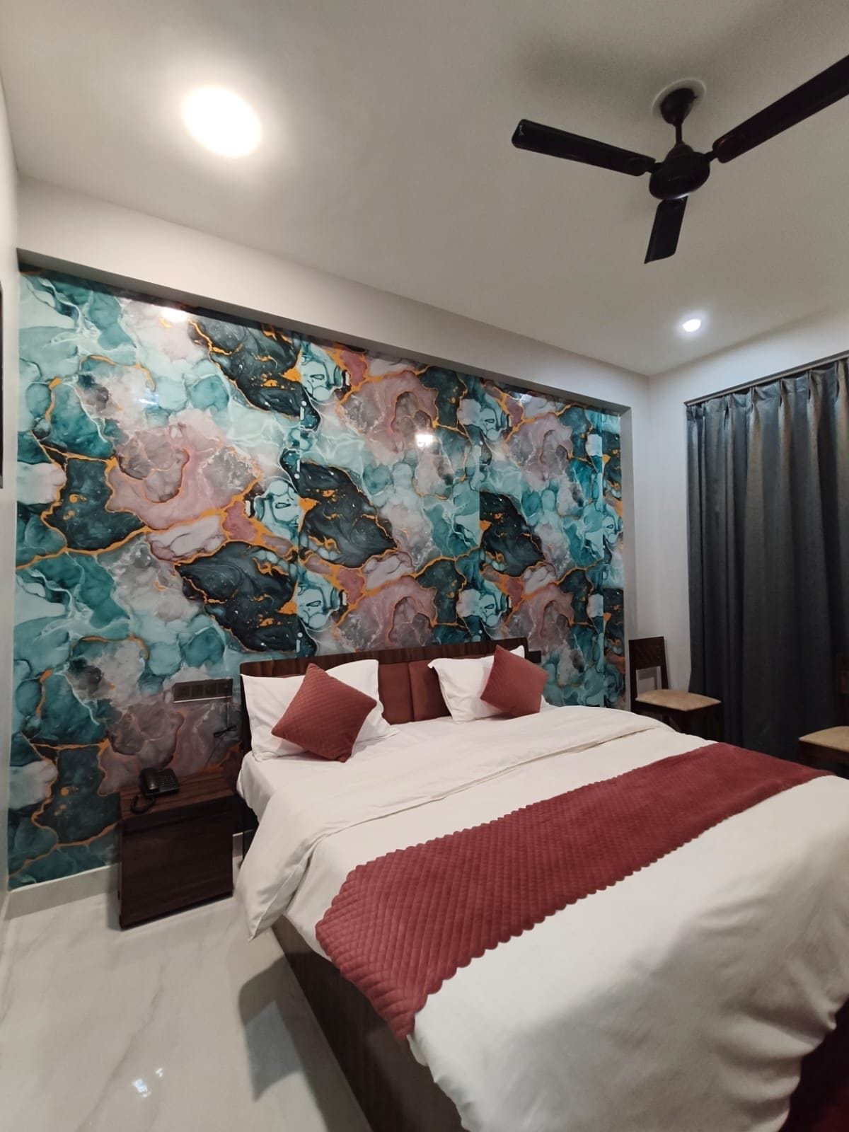 Un dormitorio moderno con una cama grande, un ventilador de techo y una pared con diseño de mármol.