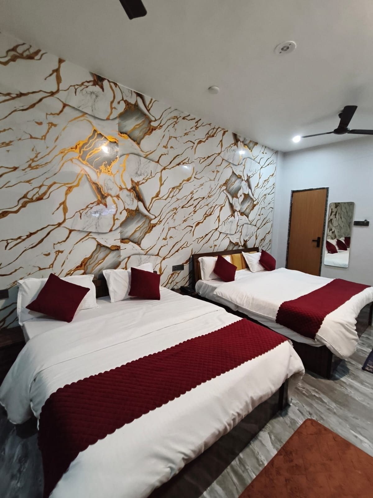 Une chambre d’hôtel avec deux lits, des murs décorés d’un motif imitant le marbre et une porte.
