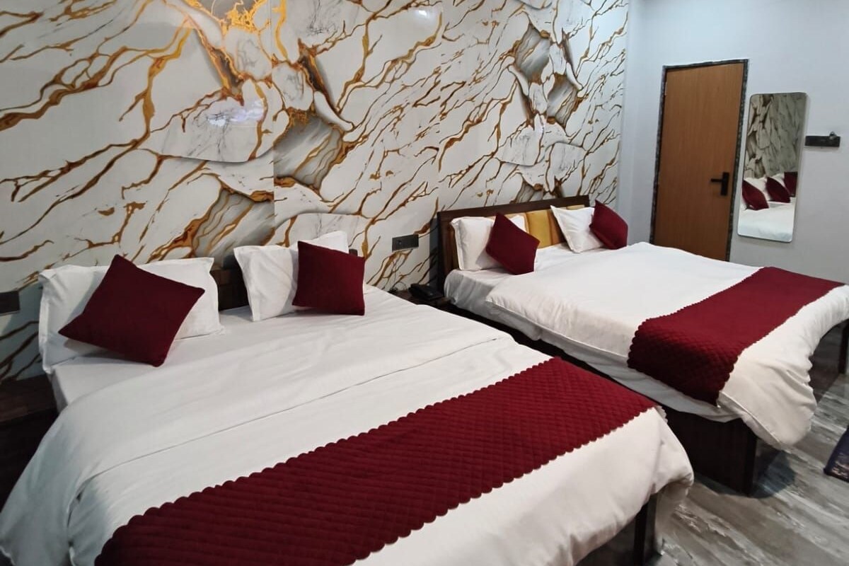 A hotel room with two beds, marble-patterned walls, and a door.