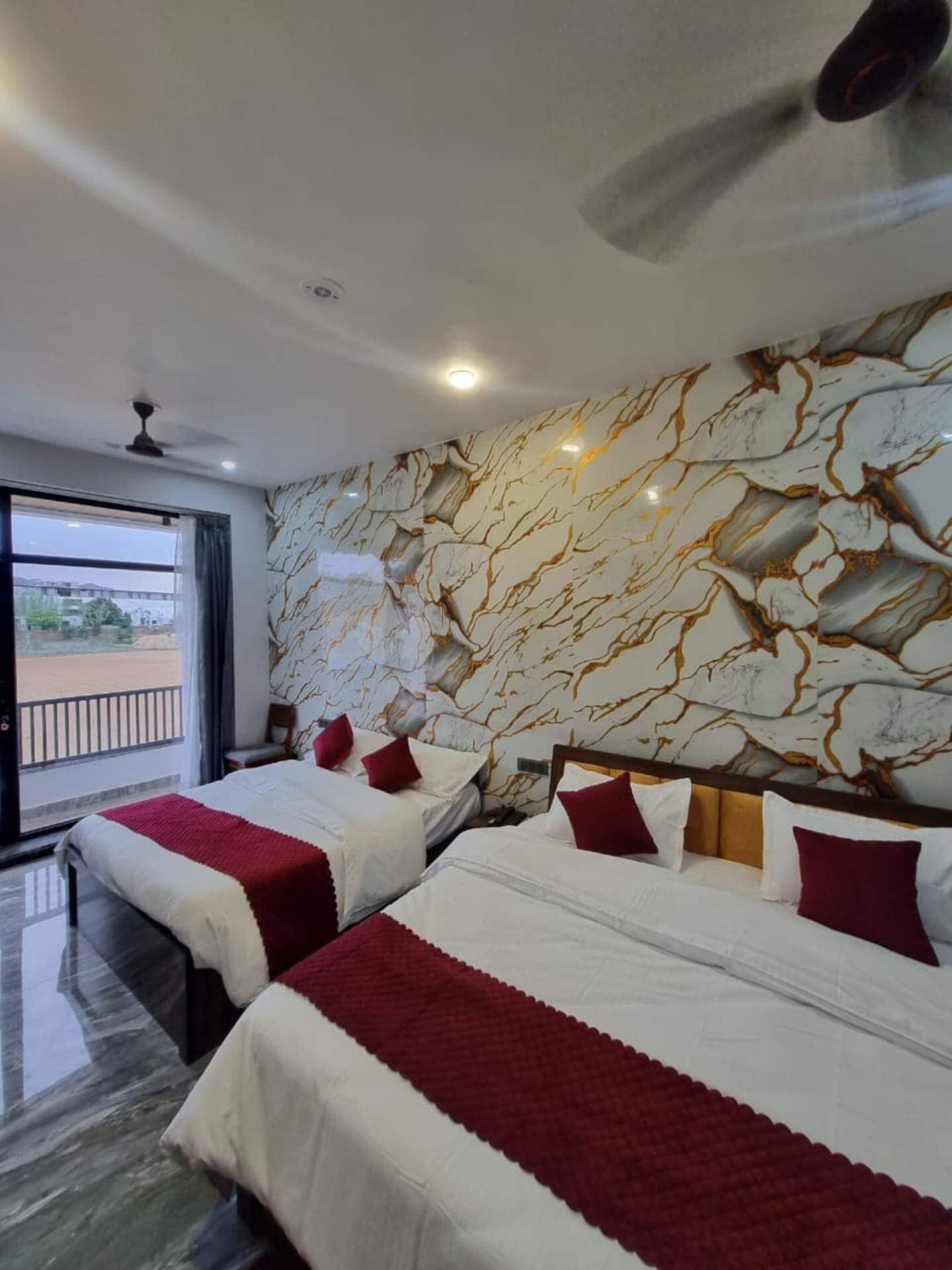 A hotel room with two beds, a marble-patterned wall, a ceiling fan, and a view through a window.