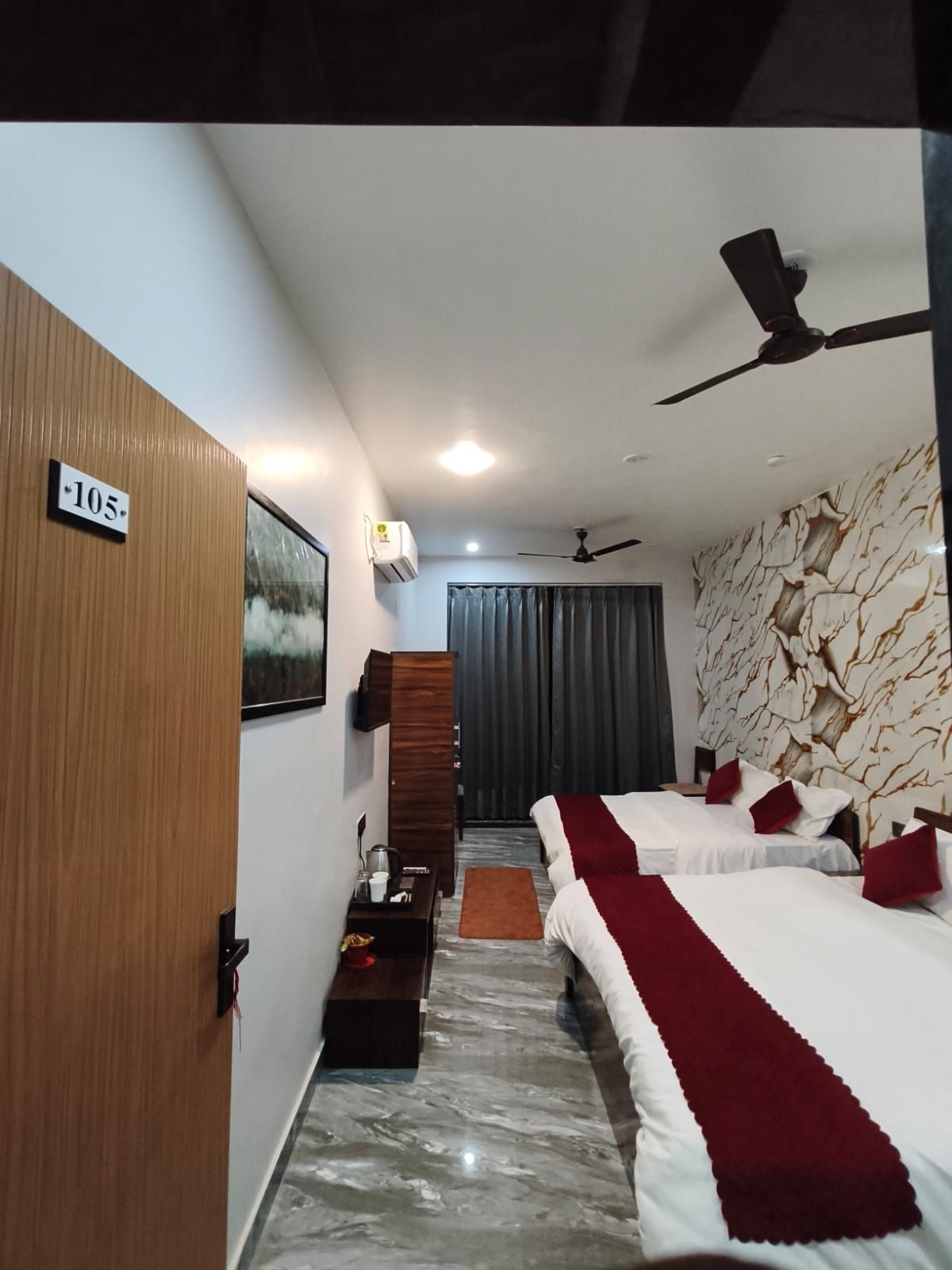 Une chambre d’hôtel équipée d’un lit, d’un bureau, d’une armoire, d’un ventilateur de plafond et d’un climatiseur fixé au mur.