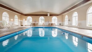 Ein Hallenbad mit klarem Wasser, umgeben von Fenstern und Liegestühlen.