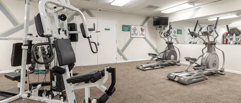 Ein Fitnessstudio mit Cardiogeräten, Kraftgeräten und einer Spiegelwand.