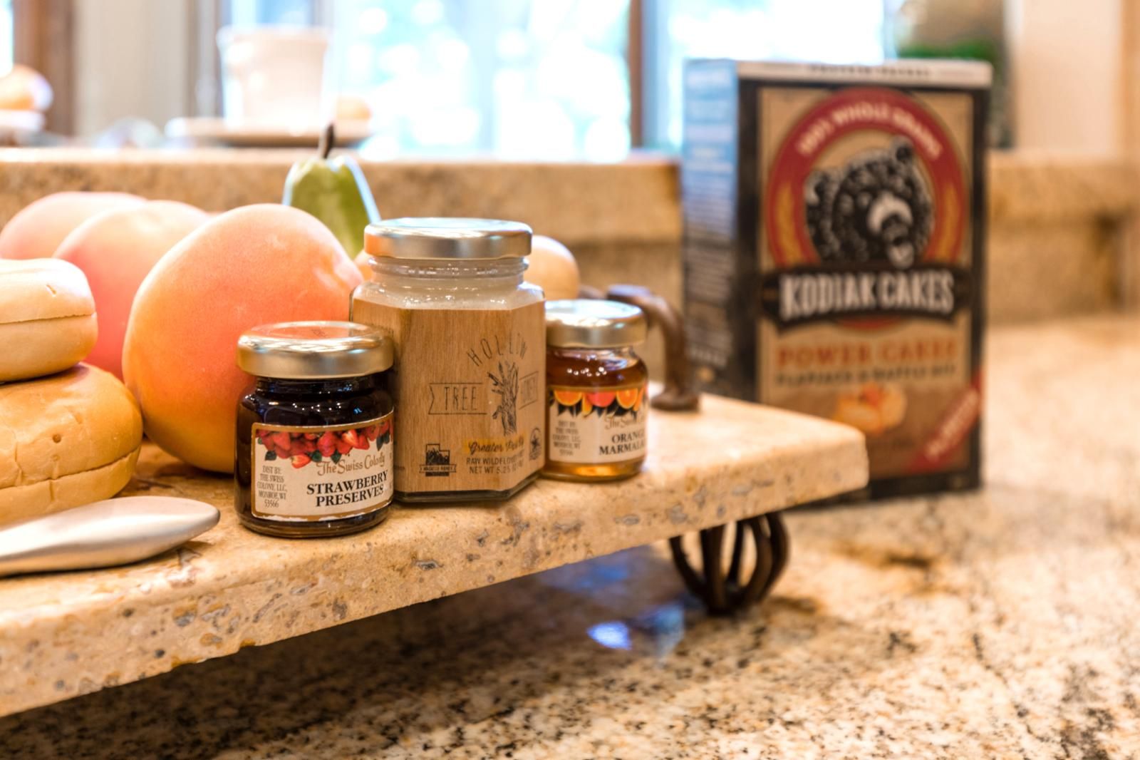 Un plan de travail de cuisine avec des pots de confitures, une boîte de biscuits KODIAK CAKES et une poire.