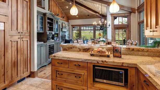 Una cucina con mobili in legno, un piano di lavoro in granito, un forno a microonde integrato e luci a sospensione.