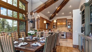 Un'area pranzo con un grande tavolo di legno, sedie a righe e un lampadario.