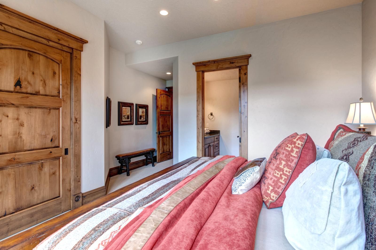 Une chambre à coucher avec un grand lit, une armoire en bois et un banc.