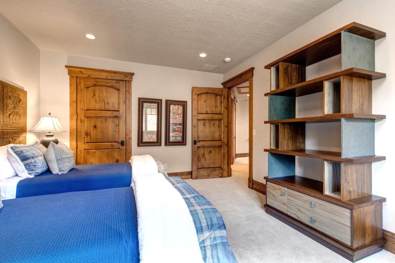 Quarto com cama grande, guarda-roupa de madeira e escrivaninha com gavetas.