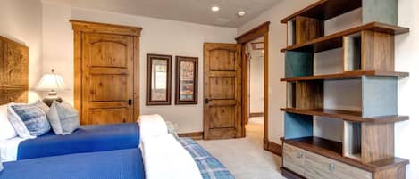 A bedroom with a large bed, wooden wardrobe, and a desk with drawers.