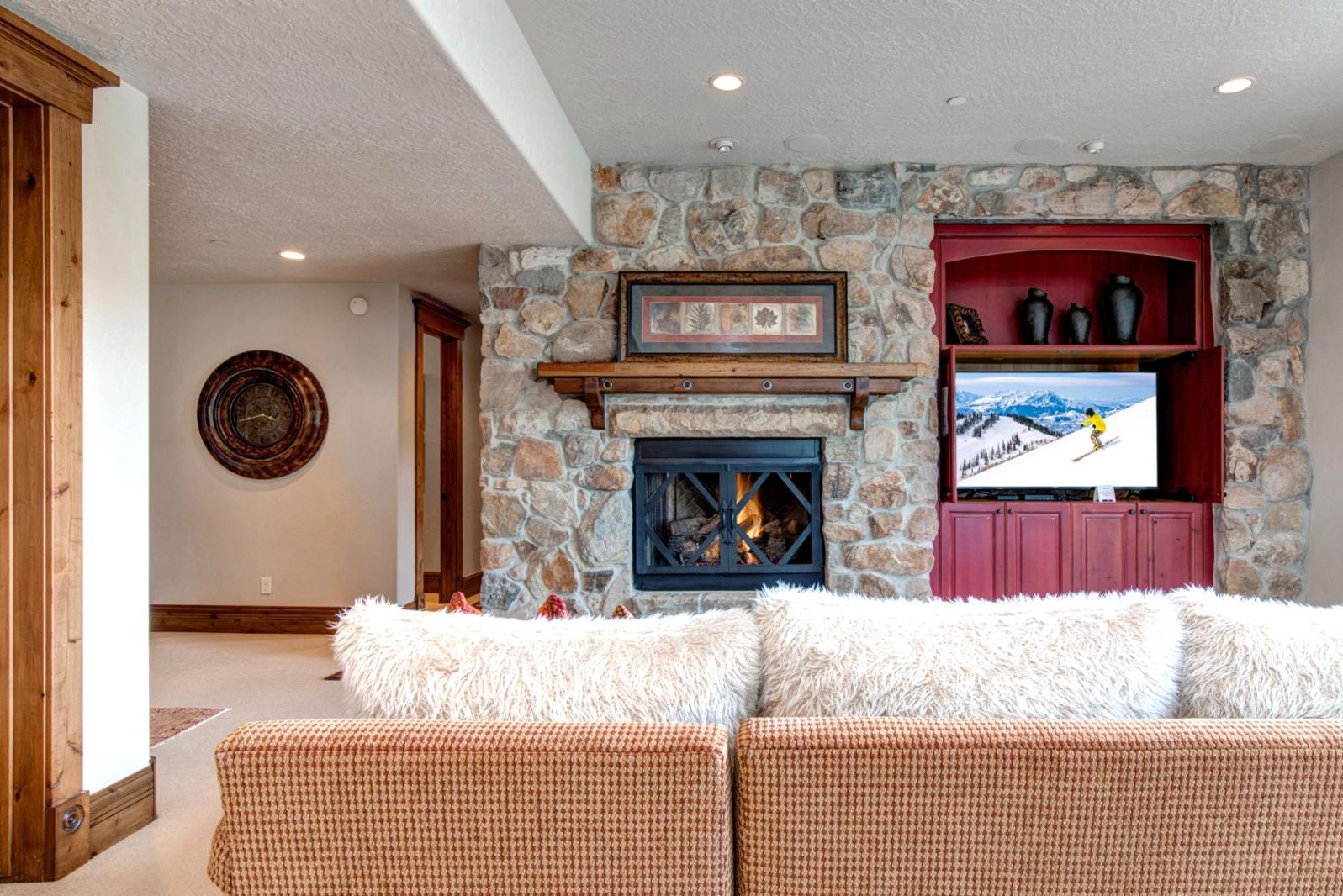 A stone fireplace with a TV above it, a wooden bench, and a fluffy white sofa.