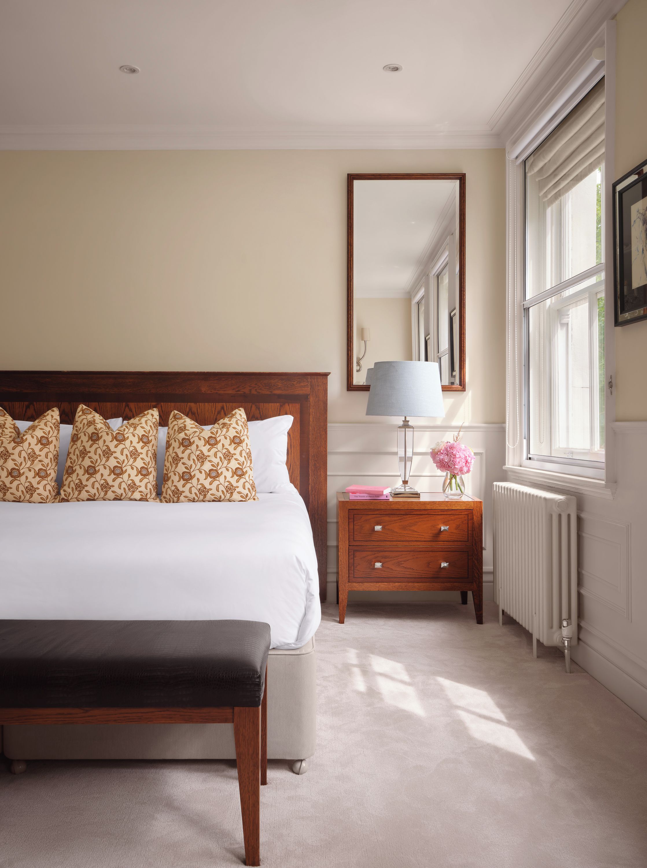 A bedroom with a large bed, bedside table, lamp, and a window with curtains.