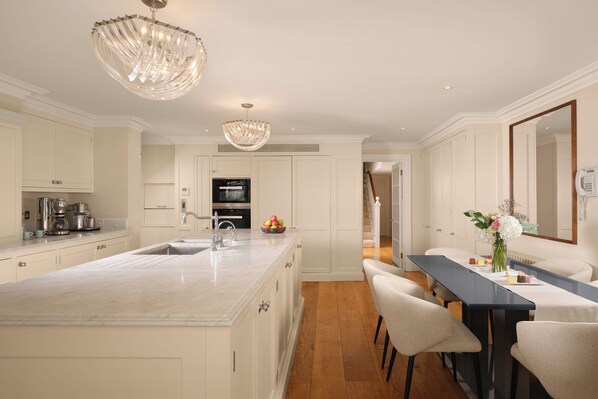 A modern kitchen with a marble island, stainless steel appliances, and a chandelier. - Mayfair's Finest | Magnificent Georgian Townhouse (London)