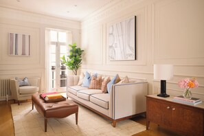 A living room with a sofa, a coffee table, a side table with a lamp, and a potted plant. - Mayfair's Finest | Magnificent Georgian Townhouse (London)