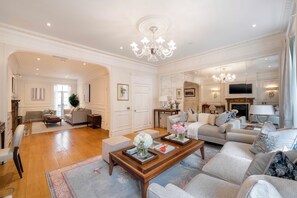 Ein geräumiges Wohnzimmer mit einer großen Sofagarnitur, einem Couchtisch und einer Chandelier.