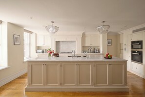 A spacious kitchen with a large island, white cabinetry, and two pendant lights.
