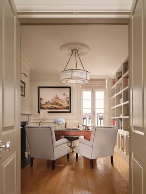 A dining area with a chandelier, a painting, and a bookshelf.