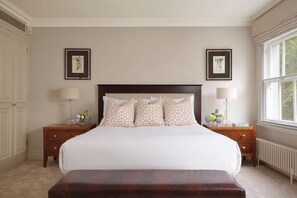 A bedroom with a large bed, two bedside tables with lamps, a wooden bench, and two framed artworks on the walls. - Mayfair's Finest | Magnificent Georgian Townhouse (London)