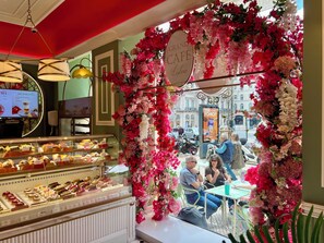 Ein Café mit einer Verkaufstheke voller Gebäck und einem Blumengestell.