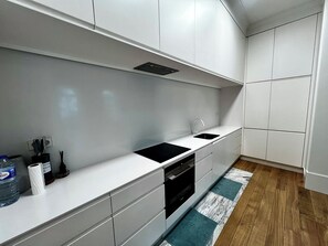 A modern kitchen with white cabinetry, a black countertop, and a wooden floor. - Luxury 3-Bedroom Apartment in Prime Central Lisbon | Terrace, Pool, Gym, and Private Parking (Lisboa)