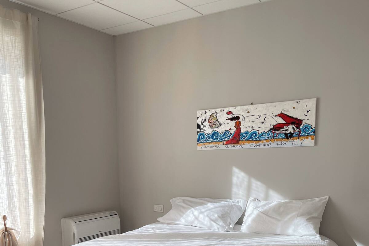 A bedroom with a bed, a radiator, and a wall with artwork.