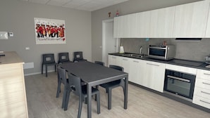 Uma cozinha moderna com armários brancos, uma mesa de jantar com cadeiras e um micro-ondas.